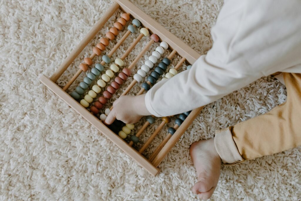 pexels-photo-6692926-6692926 A young child interacts with a colorful wooden abacus, exploring learning through play.